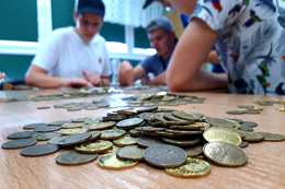 Drobne monety na biurku, w tle uczniowie